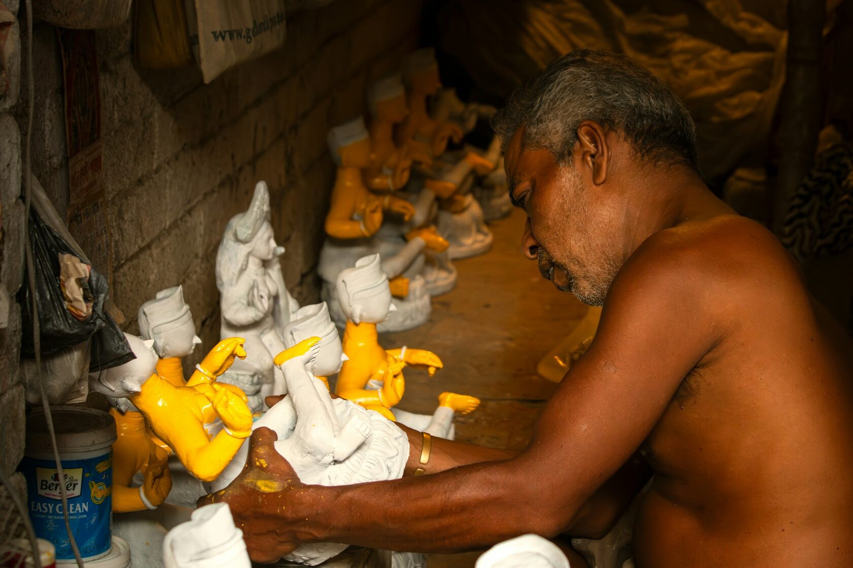 Mãos de artesão a trabalhar o mármore com cinzel e pó branco, processo tradicional de escultura